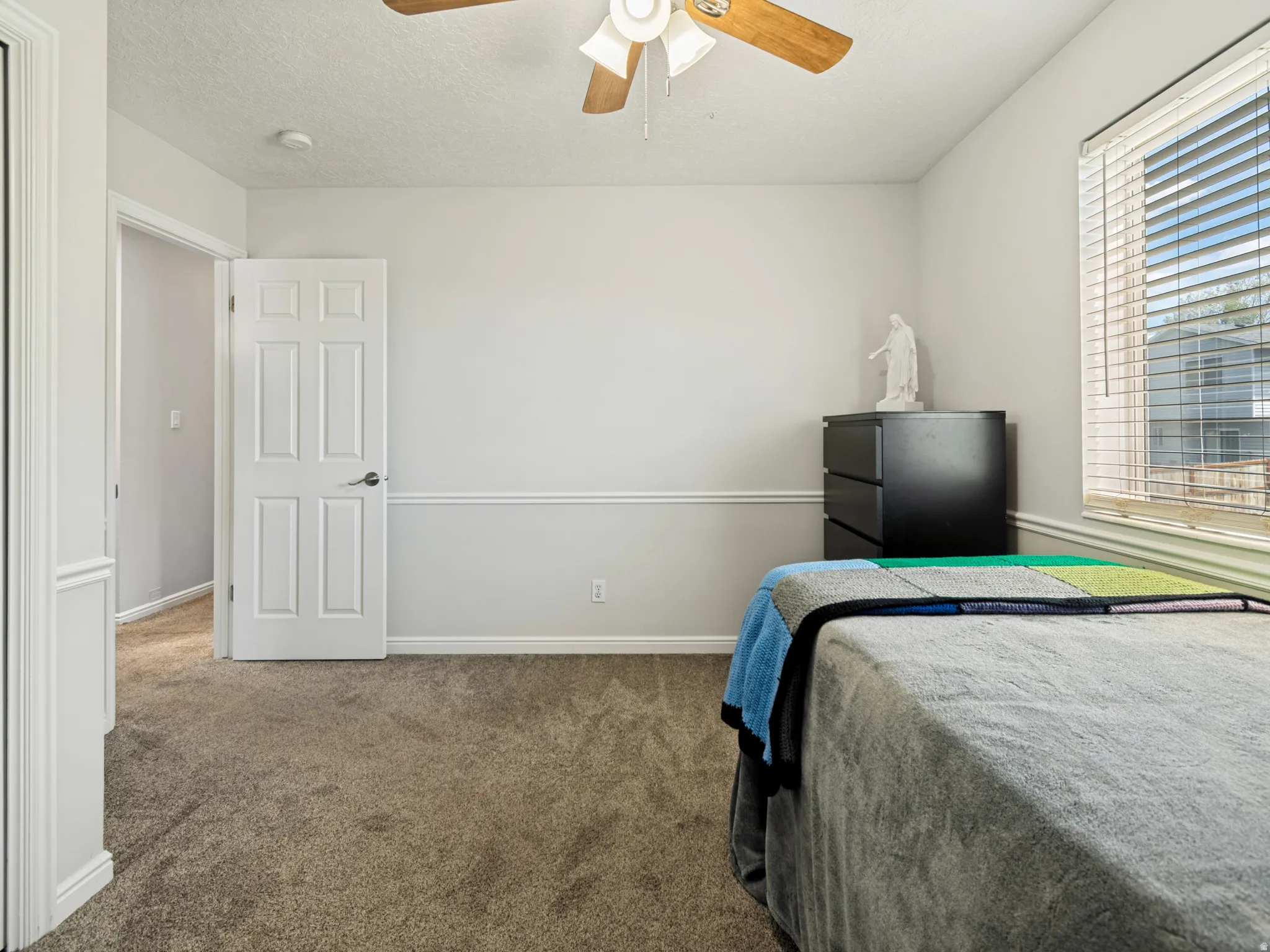 Neutral tone walls featuring wainscoting and a wood-finish ceiling fan