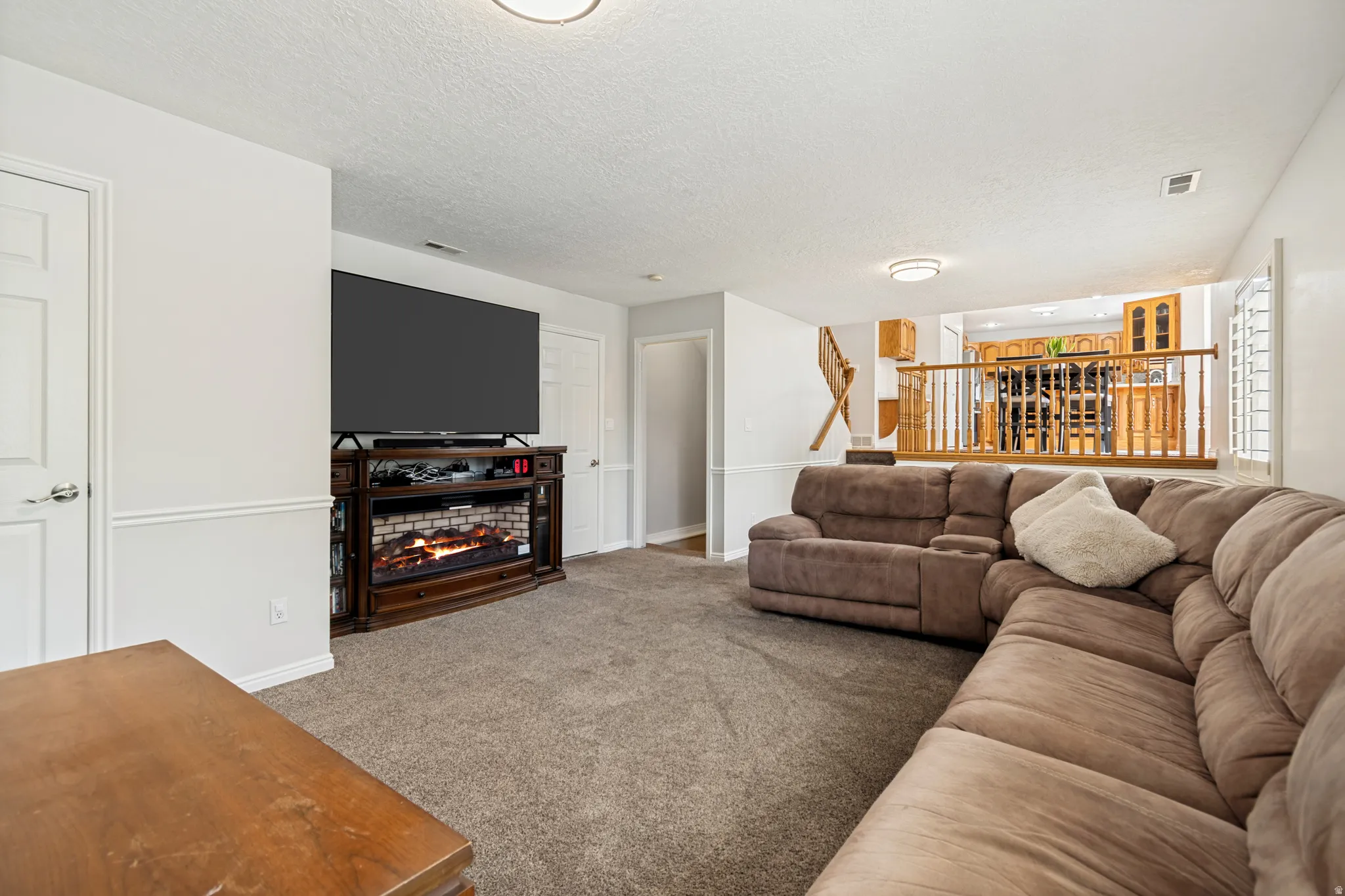 Carpeted living area featuring wainscoting, an electric fireplace with a wood-finish mantel, and recessed lighting