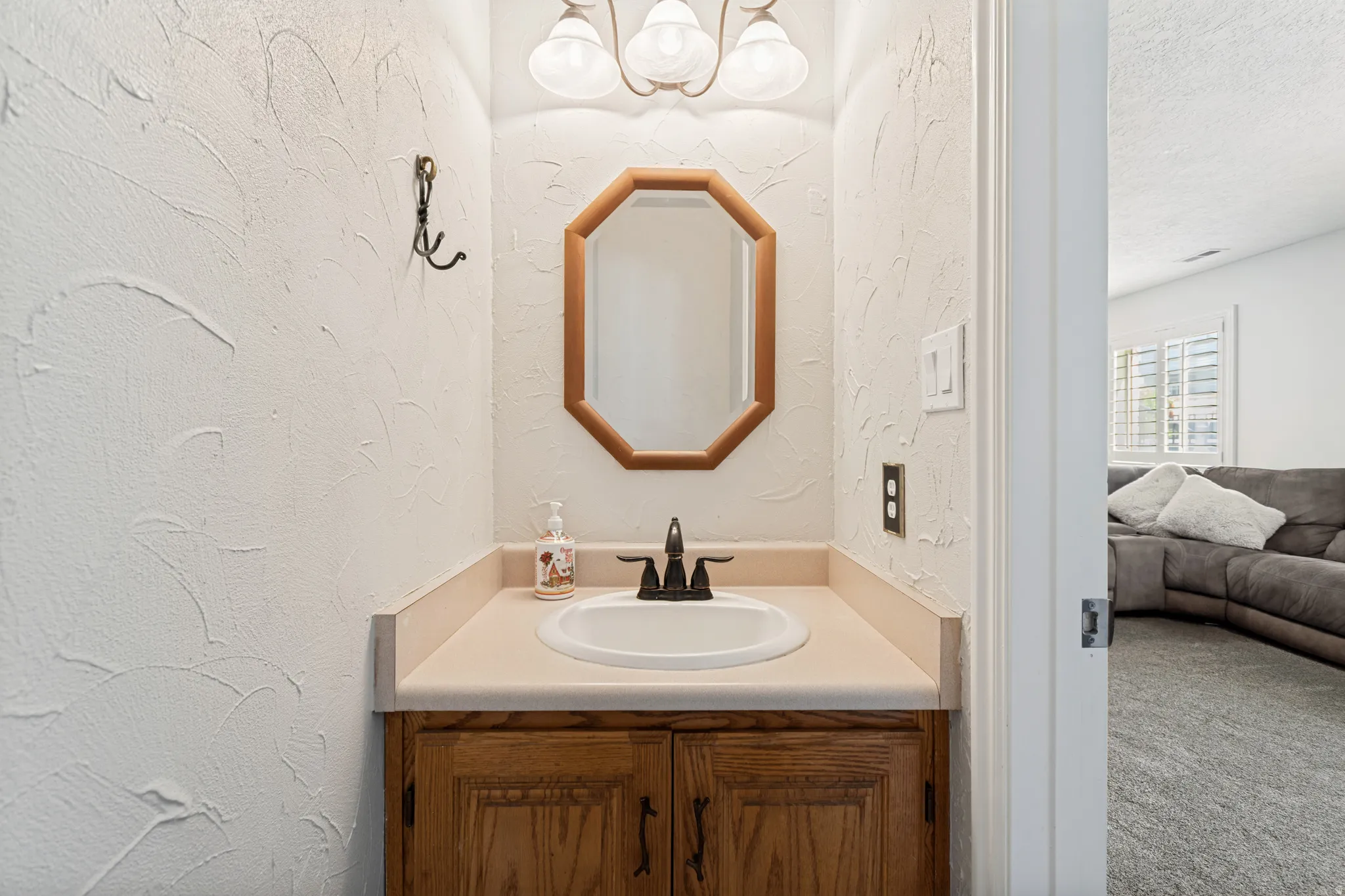 Powder room with a wood-finish vanity, light-toned countertop, and an oval undermount sink