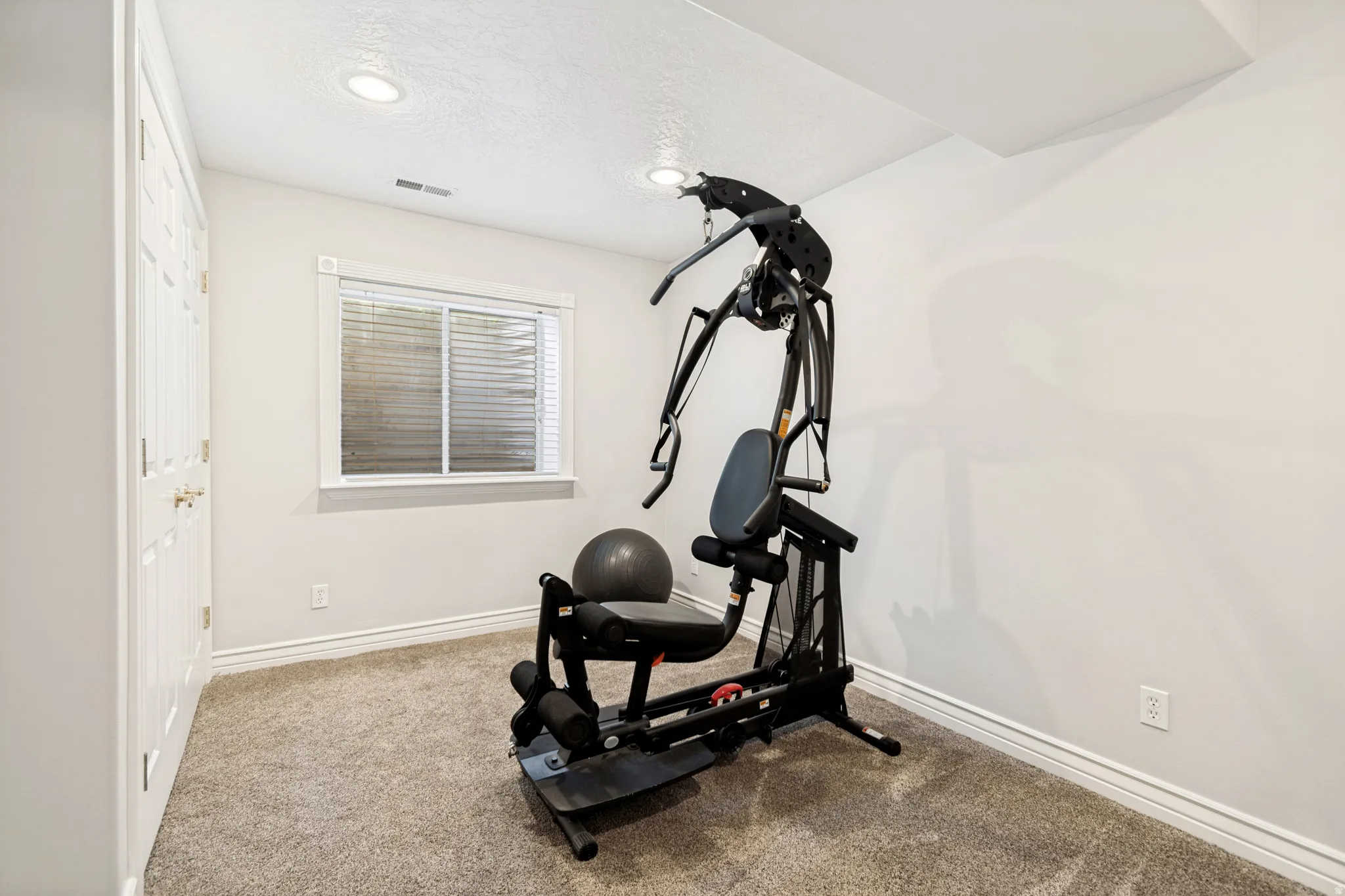 Carpeted room featuring a double-door closet, a single window with blinds, recessed lighting, and crisp white baseboards