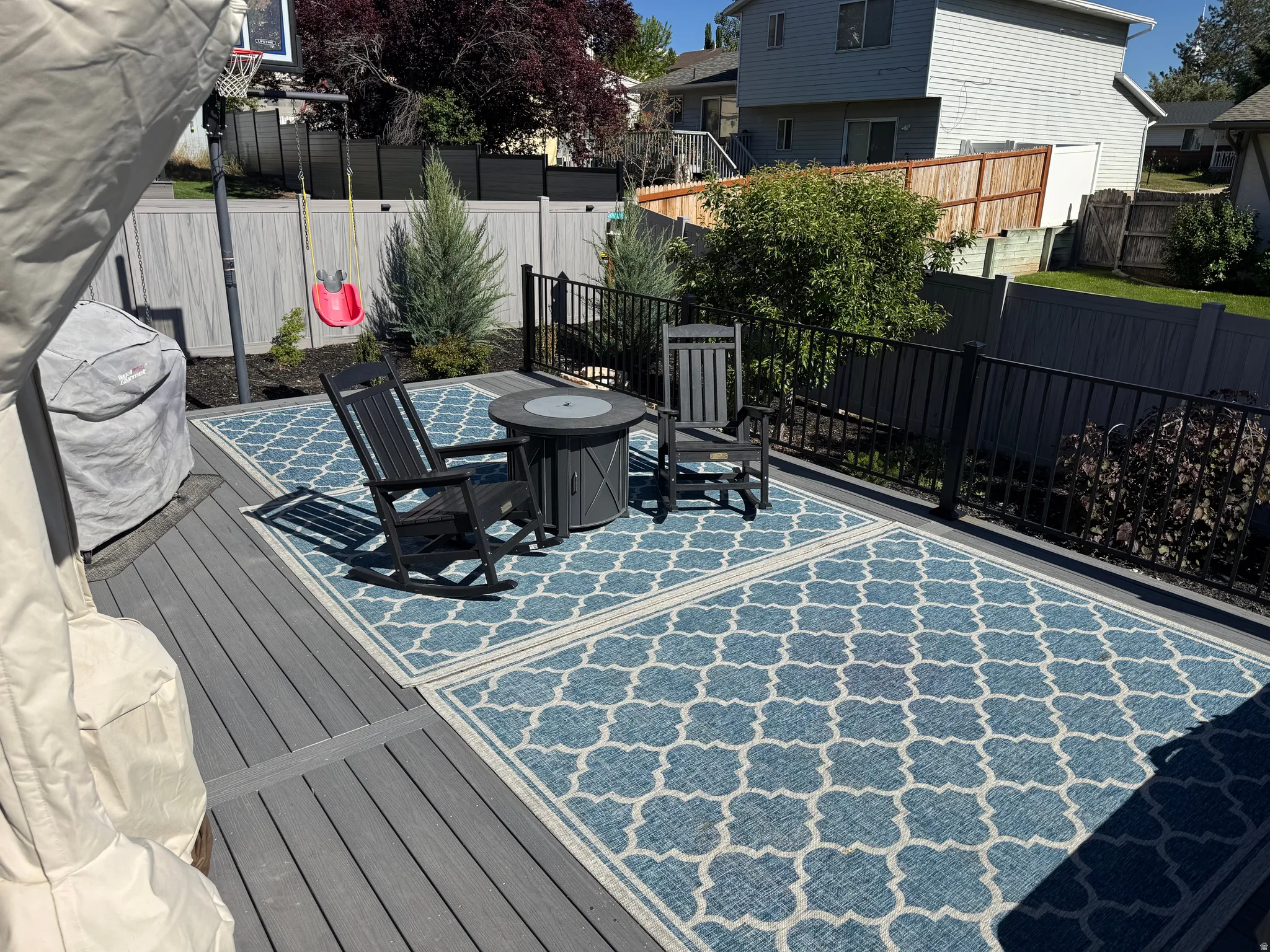 Expansive exterior deck featuring a composite wood-finish surface, black metal railing, and a gray privacy fence