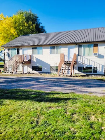 Multi-unit residence featuring a metal roof, light-colored siding, and individual exterior staircases providing access to upper-level units