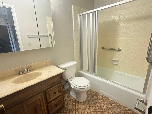 Bathroom with a wood-finish vanity, integrated countertop sink, and a mirrored medicine cabinet