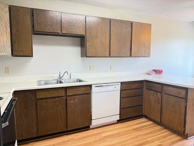 Kitchen featuring wood-finish cabinetry, light countertops, and wood-finish flooring