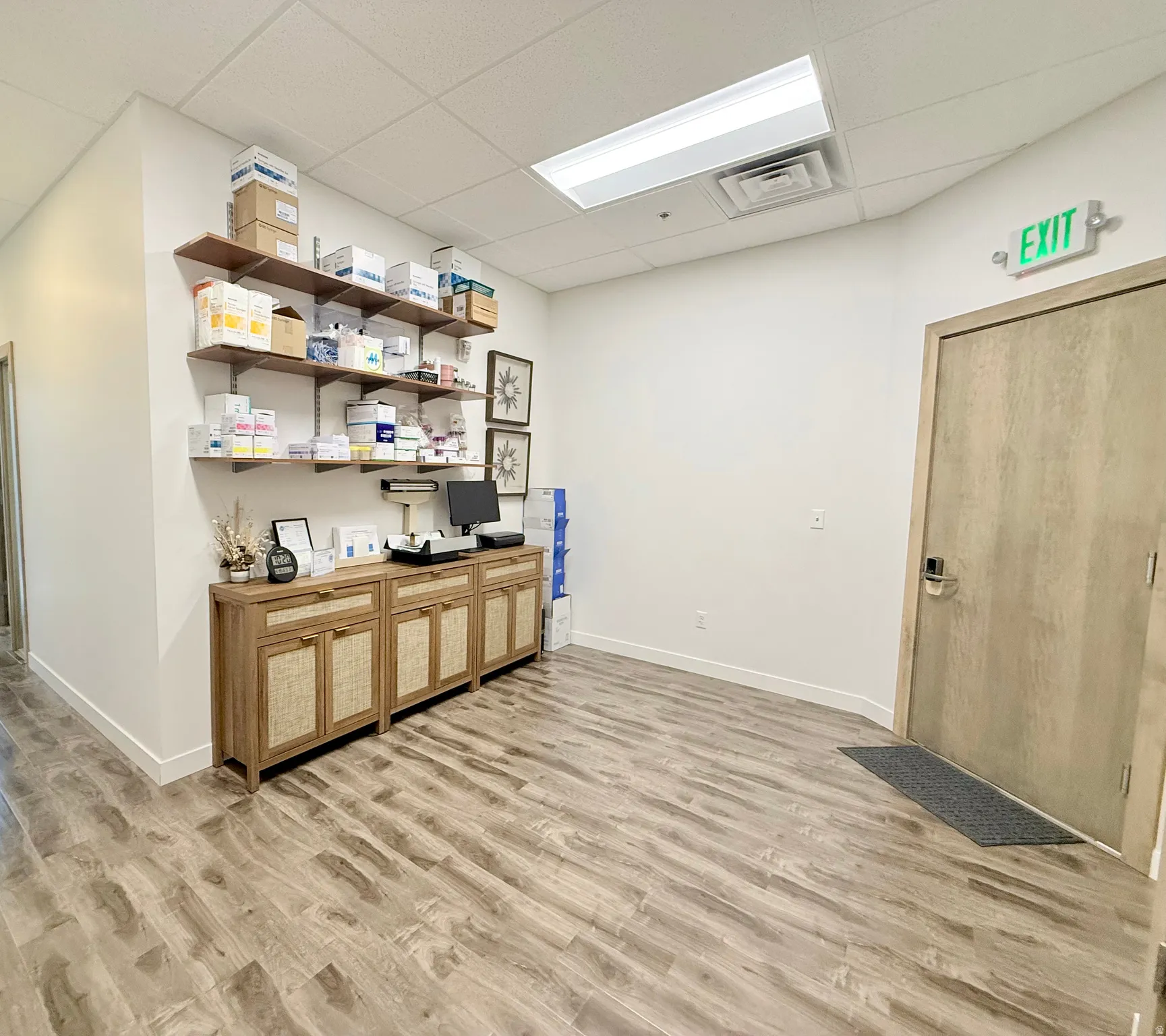 Spacious room featuring wood-finish flooring, white walls, and a recessed ceiling with fluorescent lighting
