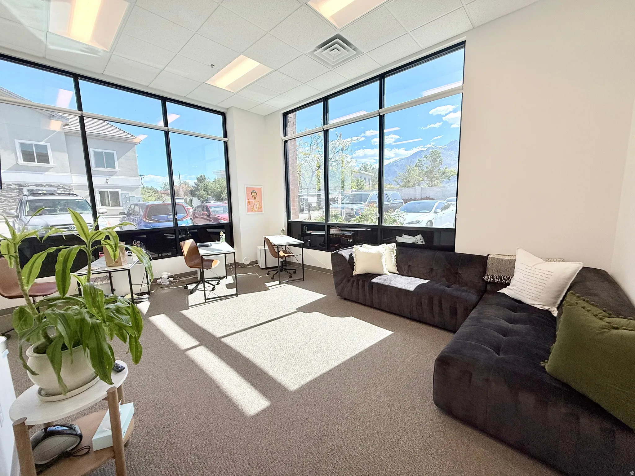 Office space featuring expansive windows, neutral wall tones, and carpet flooring