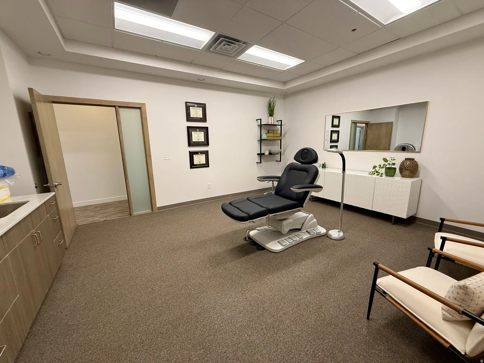 Commercial space featuring broadloom carpet flooring, recessed lighting, and a built-in wood-finish cabinet with a sink