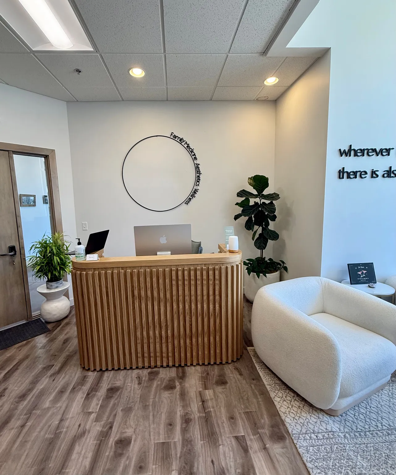 Lobby area featuring a slatted wood-finish reception desk, wood-finish flooring, and recessed lighting