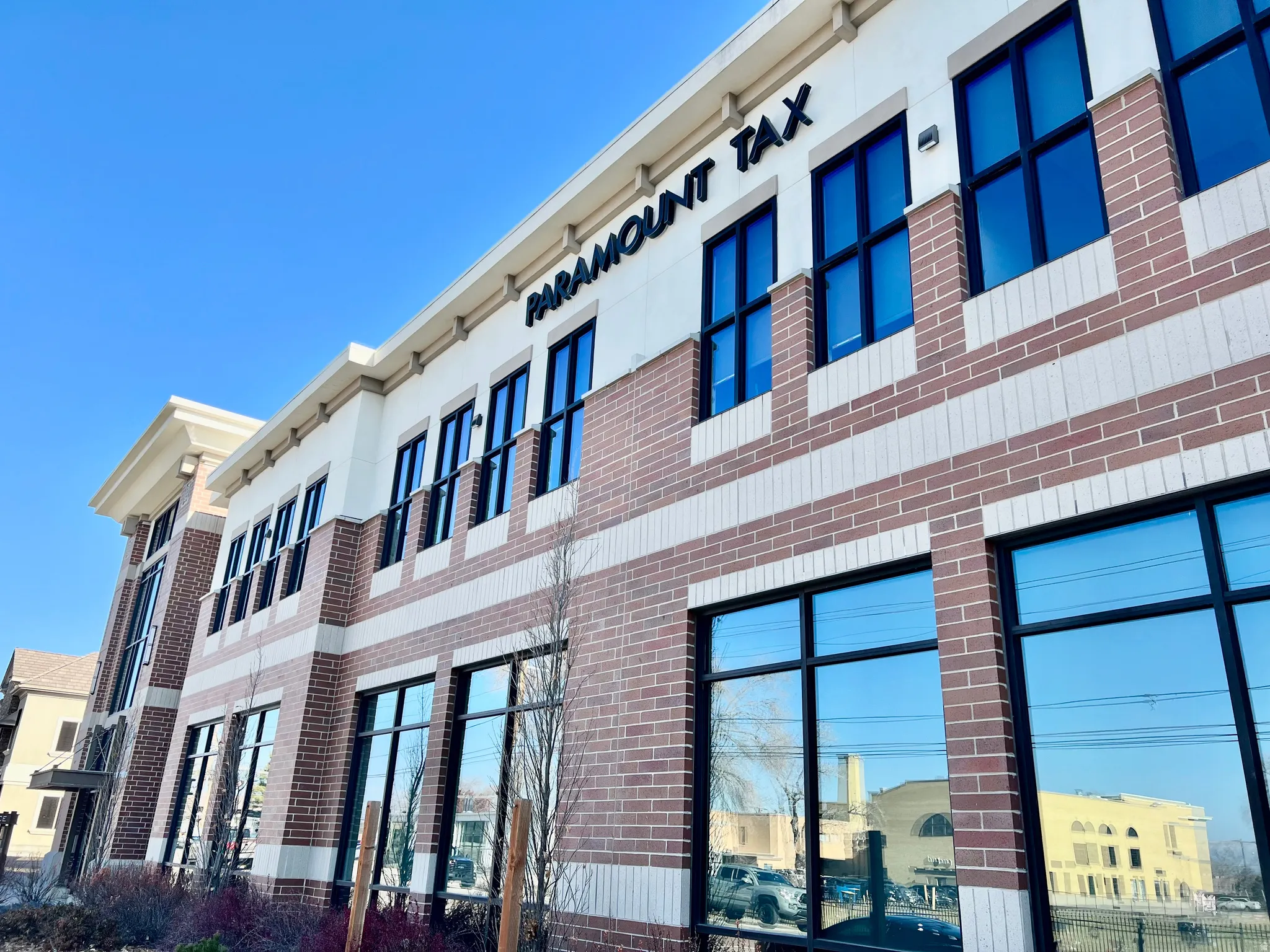 Modern commercial building featuring a brick and stone facade, large black-framed windows, and decorative cornices