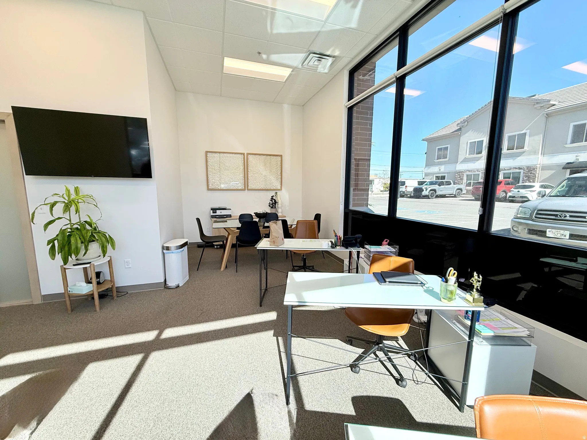 Open-concept office space featuring extensive window walls, recessed lighting, neutral carpet flooring, and white painted walls