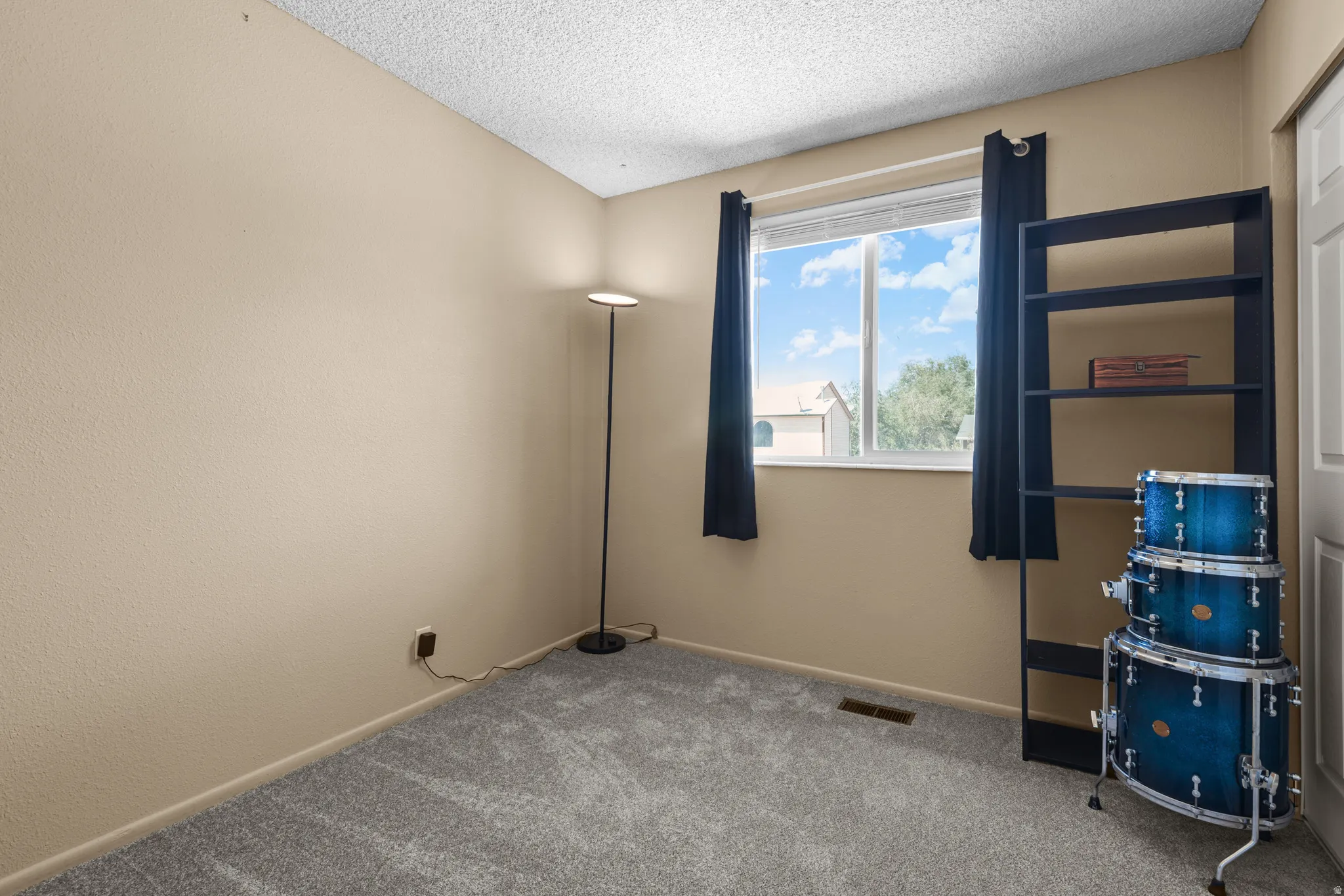 Room featuring neutral-toned walls, textured ceiling, and grey carpet flooring