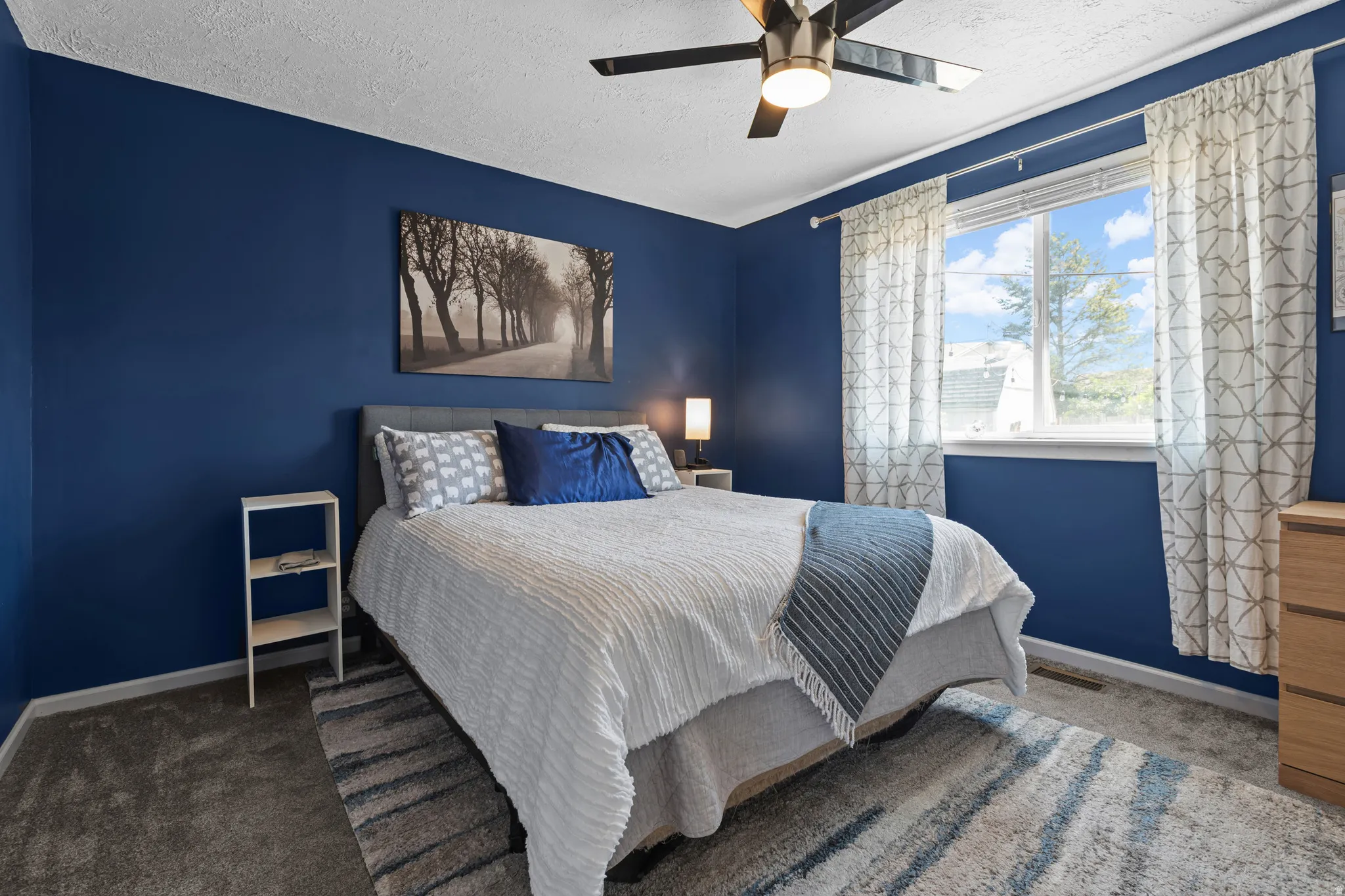 Bedroom featuring a double-pane window, flush-mount ceiling fan, and blue painted walls