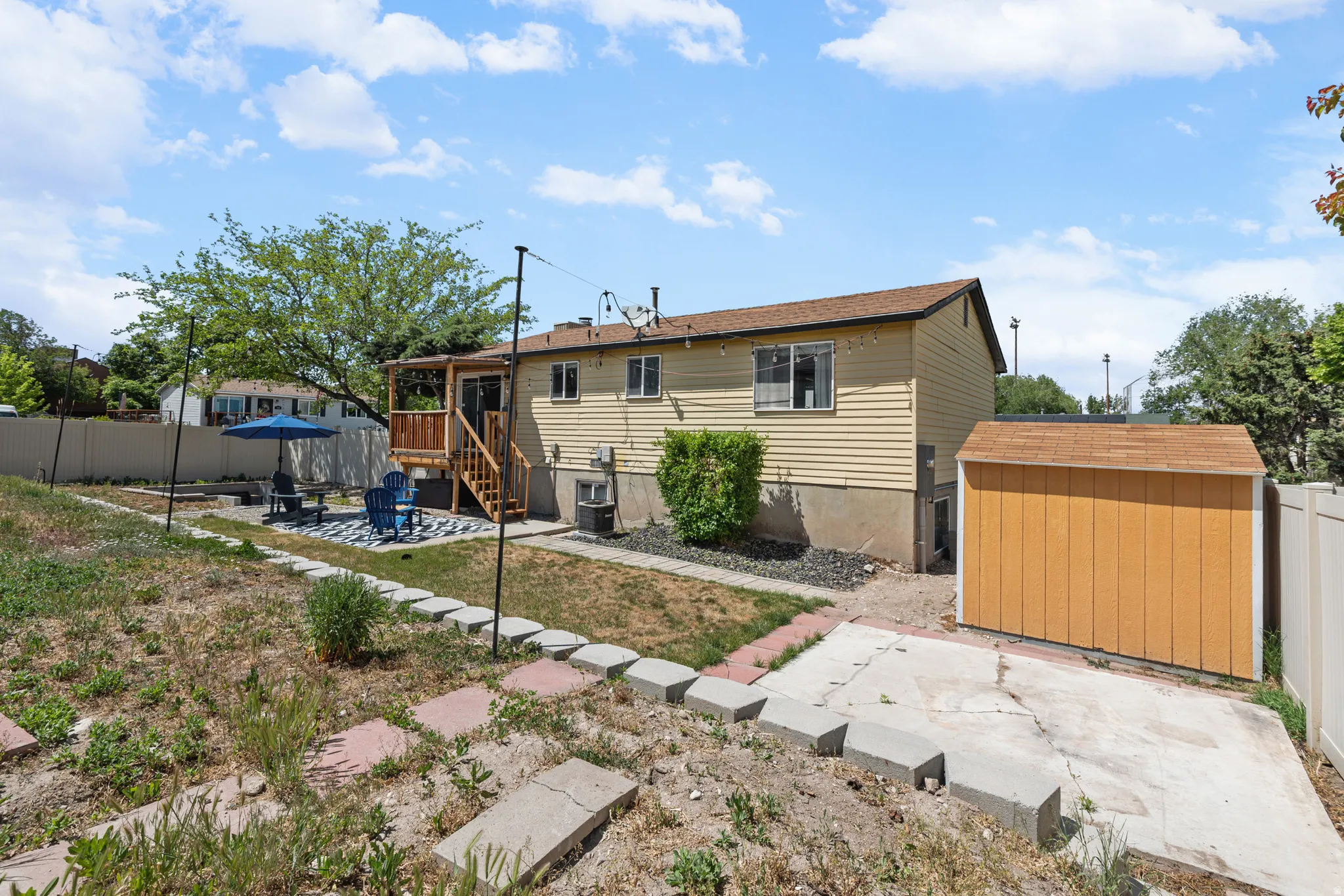Expansive backyard featuring a wood deck with stairs, a patio area, and a separate storage shed