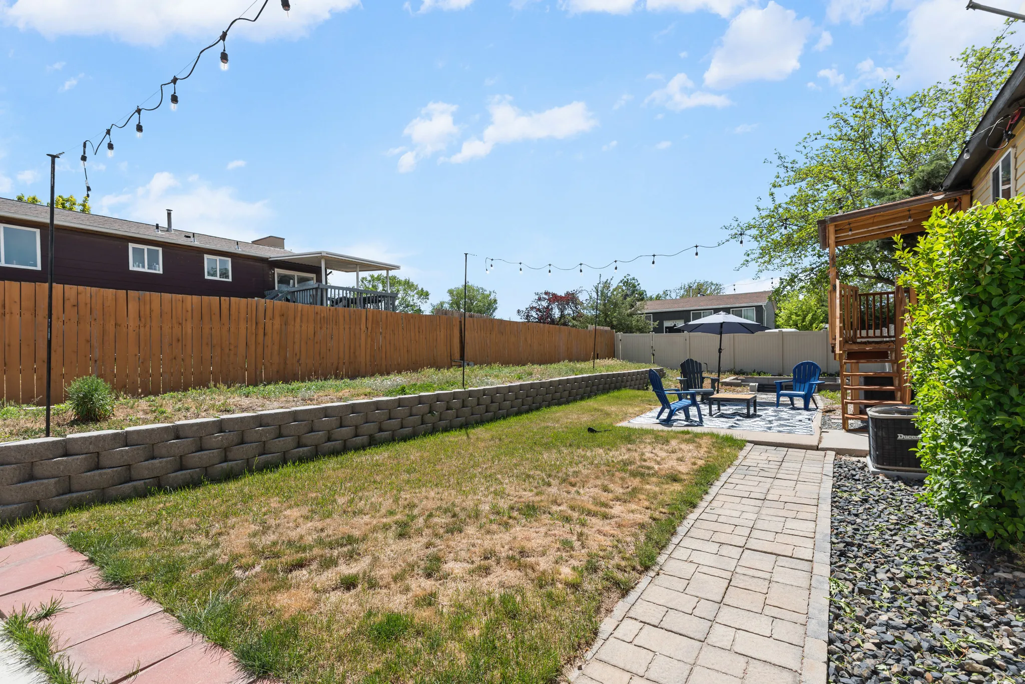Spacious backyard featuring a paver patio area, built-in retaining wall, and a wood privacy fence