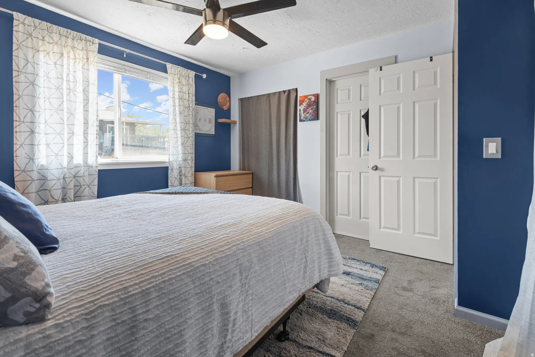 Carpeted room featuring a ceiling fan with integrated lighting, a window with white trim, and a built-in closet with paneled bifold doors