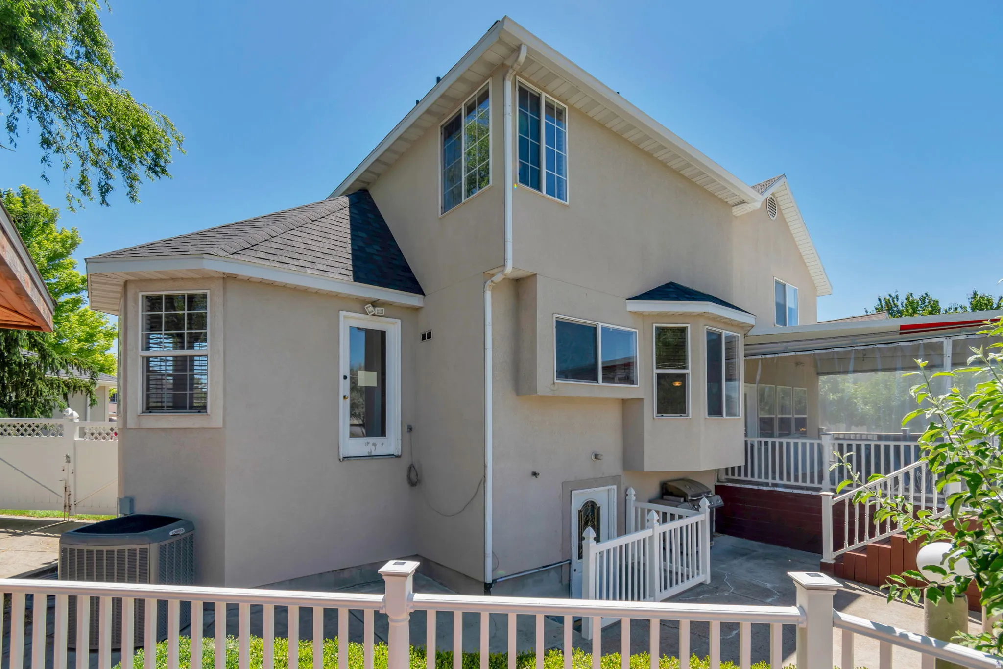 Exterior featuring stucco siding, multiple windows with grid patterns, a bay window, and a shingled roof