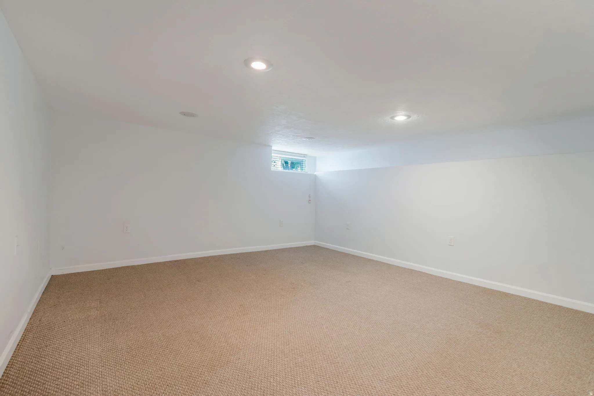 Finished room featuring recessed lighting, a neutral carpet, white walls, and a window for natural light