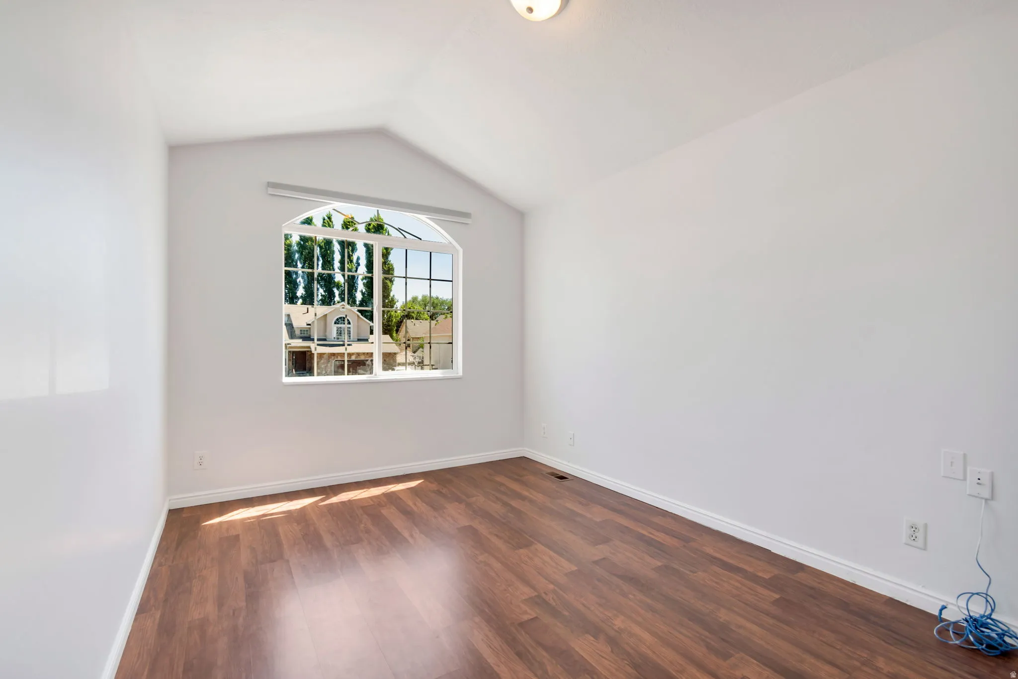 Room featuring a vaulted ceiling and an arched window