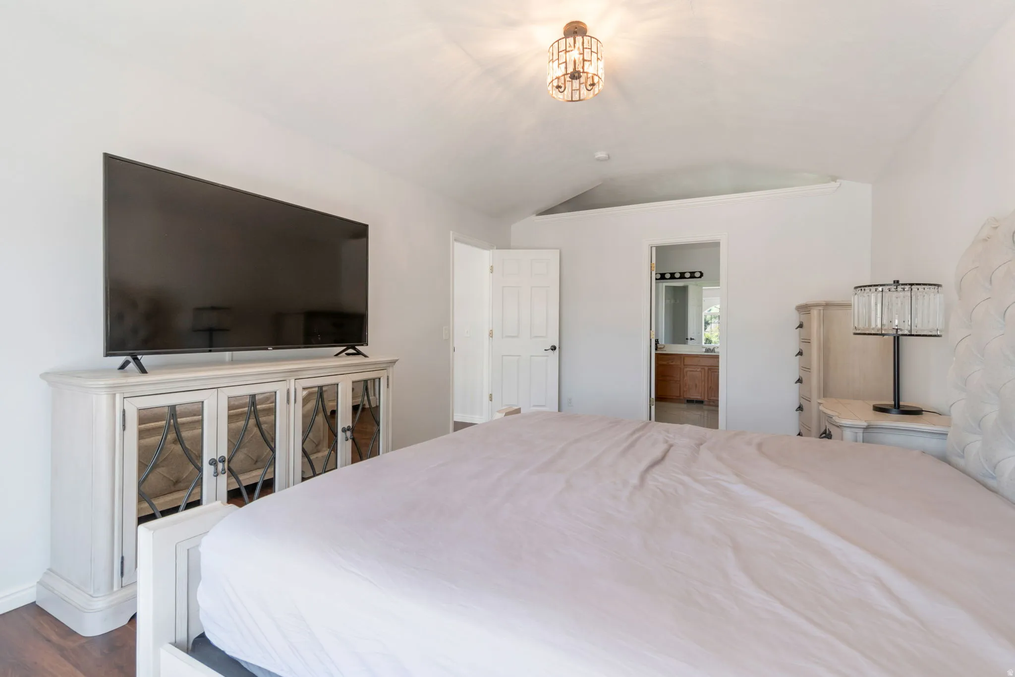 Vaulted ceiling bedroom featuring wood-finish flooring and a decorative ceiling light fixture