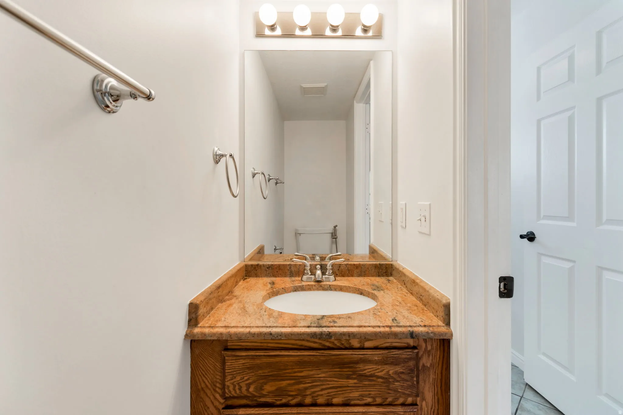 Vanity with a light wood-finish base, integrated white basin, and a speckled countertop