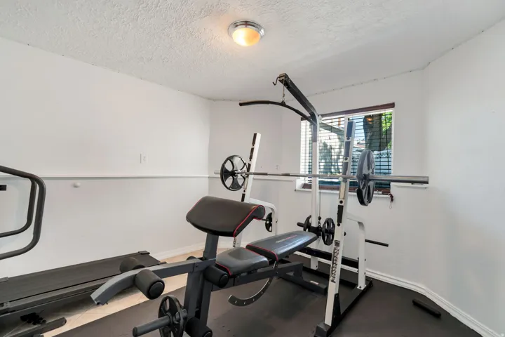 Dedicated room featuring a window with horizontal blinds, a ceiling-mounted light fixture, white walls, and a textured ceiling