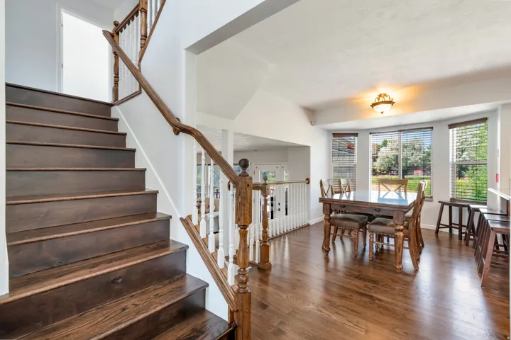 Hardwood staircase with white balusters and a wood-finish handrail