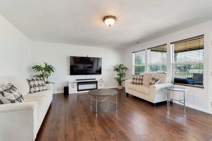 Spacious living area featuring rich wood-finish flooring and abundant natural light through multiple windows