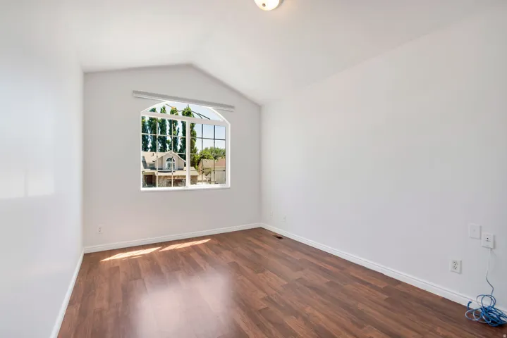 Room featuring a vaulted ceiling and an arched window