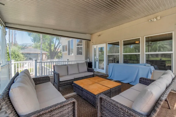 Covered patio featuring a slatted ceiling, multiple windows, and a glass-paneled door