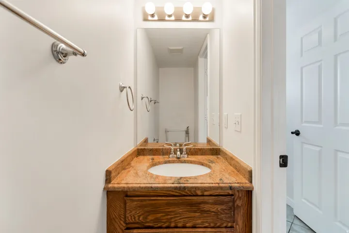 Vanity with a light wood-finish base, integrated white basin, and a speckled countertop