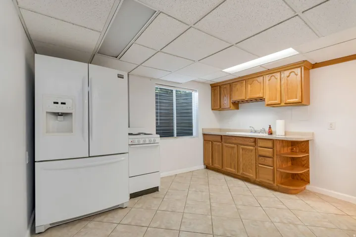 Compact kitchen area featuring a white French door refrigerator, white electric range, and light-toned wood cabinetry with integrated shelving