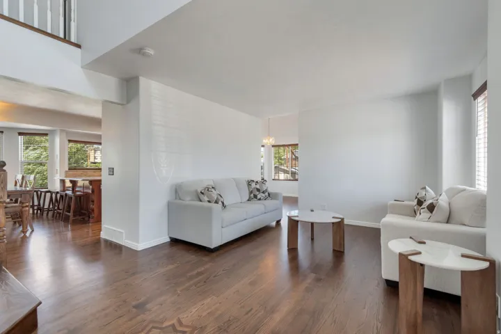 Expansive living area featuring rich wood-finish flooring with an inlaid pattern