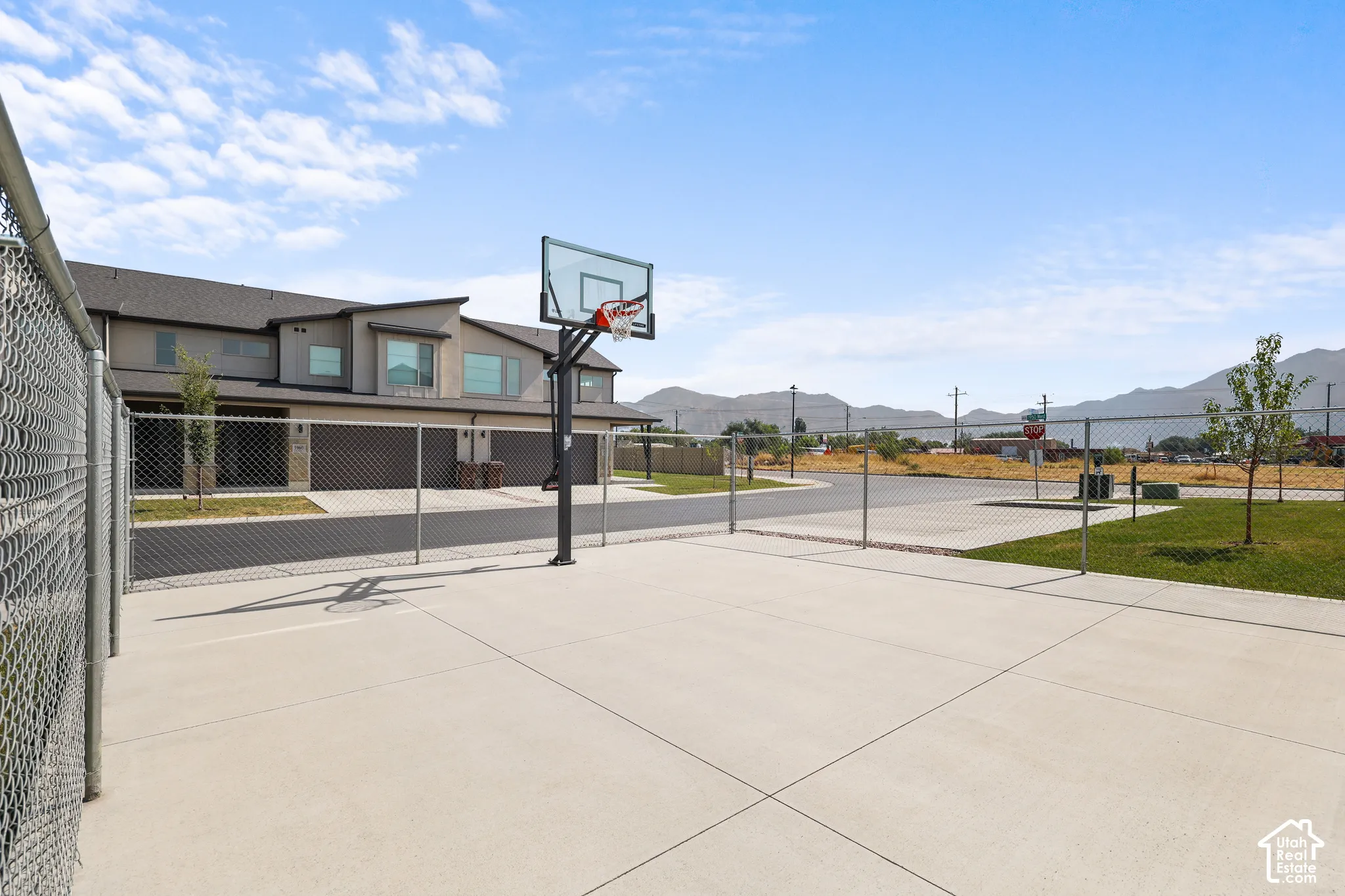 Concrete court with a chain-link fence enclosure and a basketball hoop