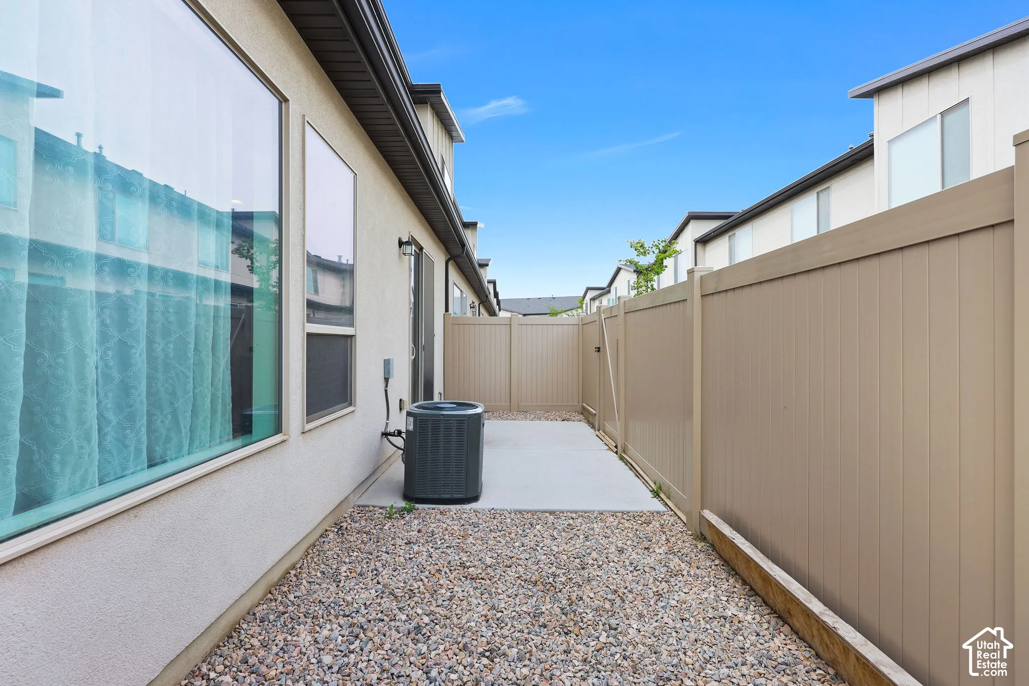 Side yard featuring a concrete patio, gravel landscaping, and tall privacy fencing