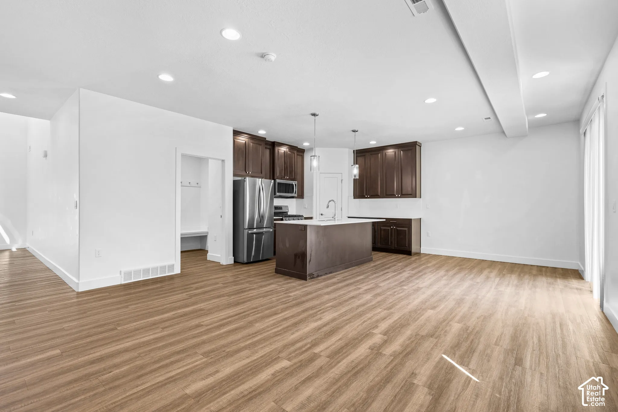 Kitchen featuring dark wood-finish cabinetry, stainless steel appliances, and a central island with pendant lighting