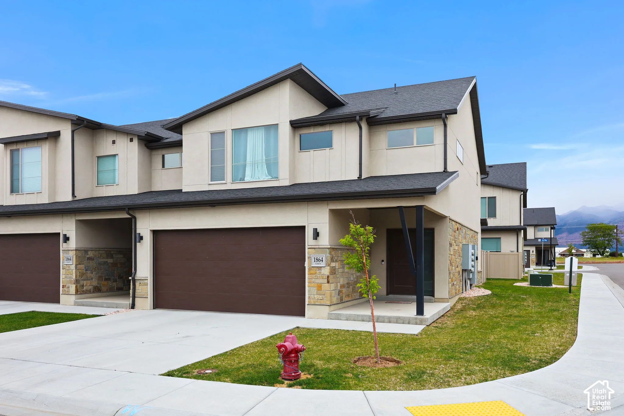 Modern townhome exterior with a light stucco finish and dark trim
