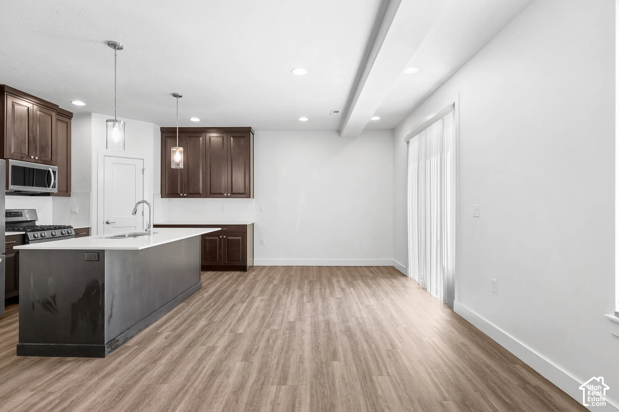 Open-concept living space with wood-finish flooring, recessed lighting, and a sliding glass door