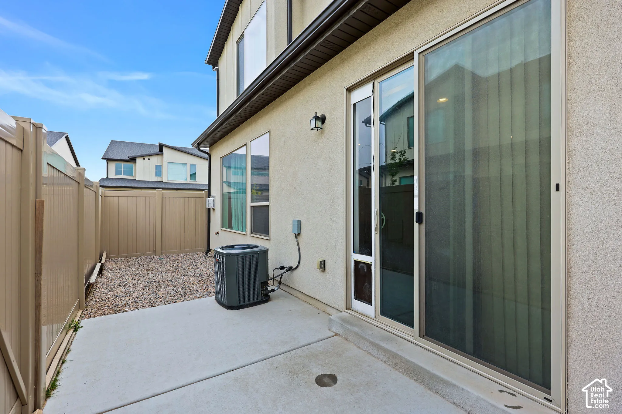 Exterior concrete patio with a full-height privacy fence and an adjacent gravel area