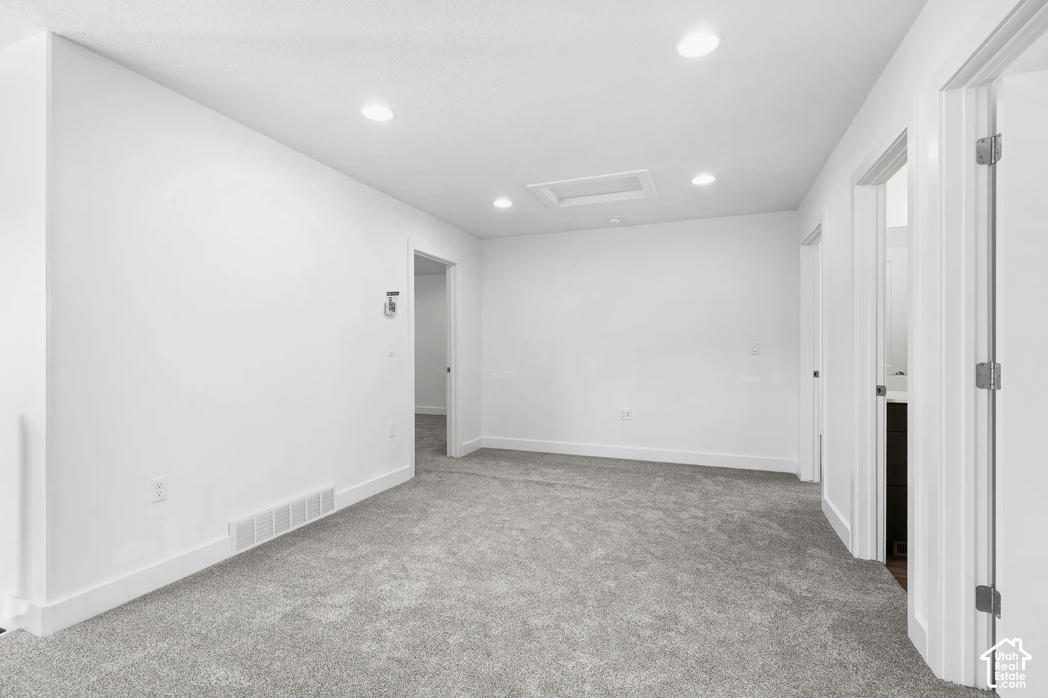 Plush carpet flooring, recessed ceiling lighting, and white trim throughout