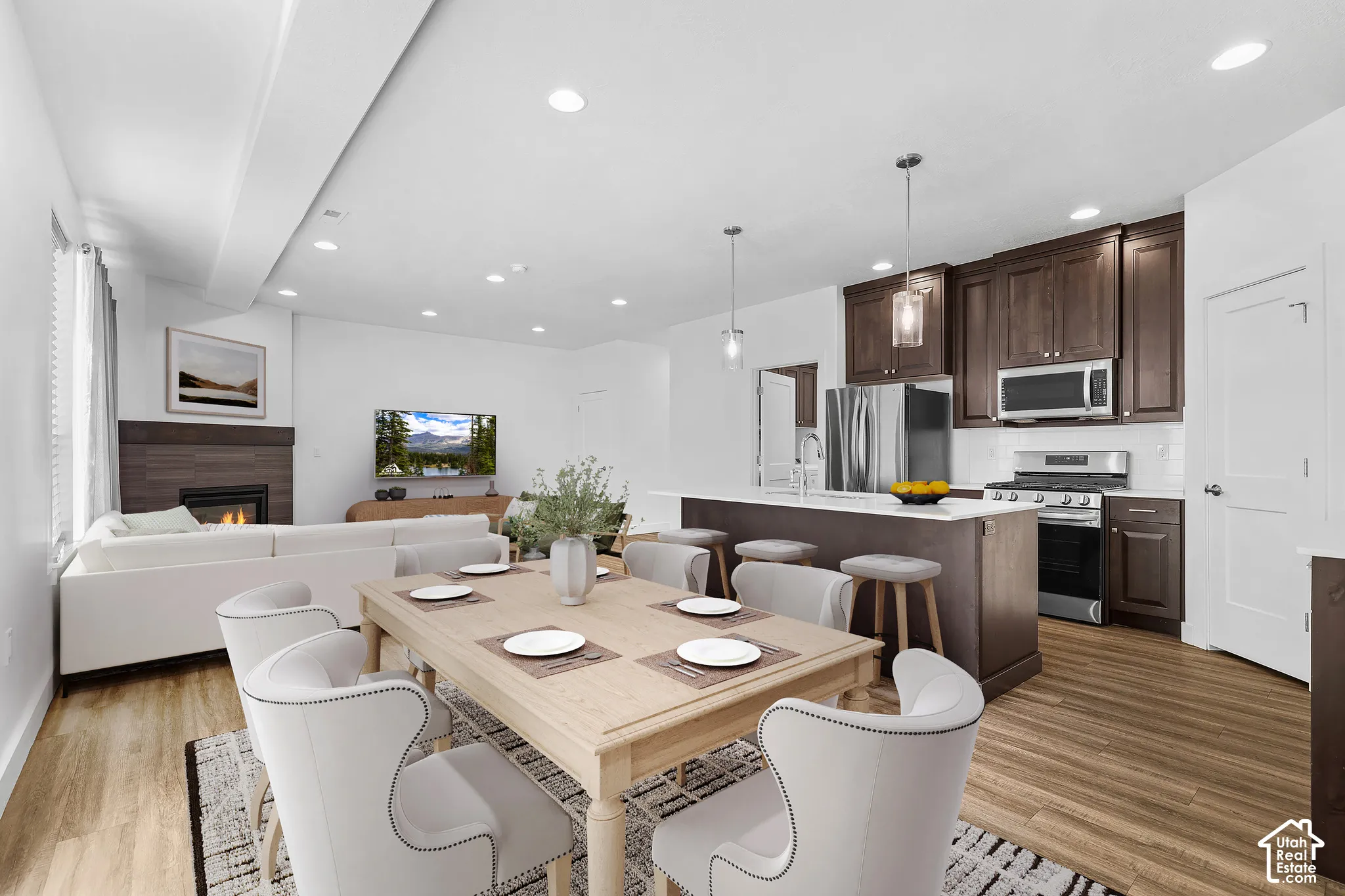 Open-concept living space with wood-finish flooring, a contemporary fireplace, and recessed lighting
