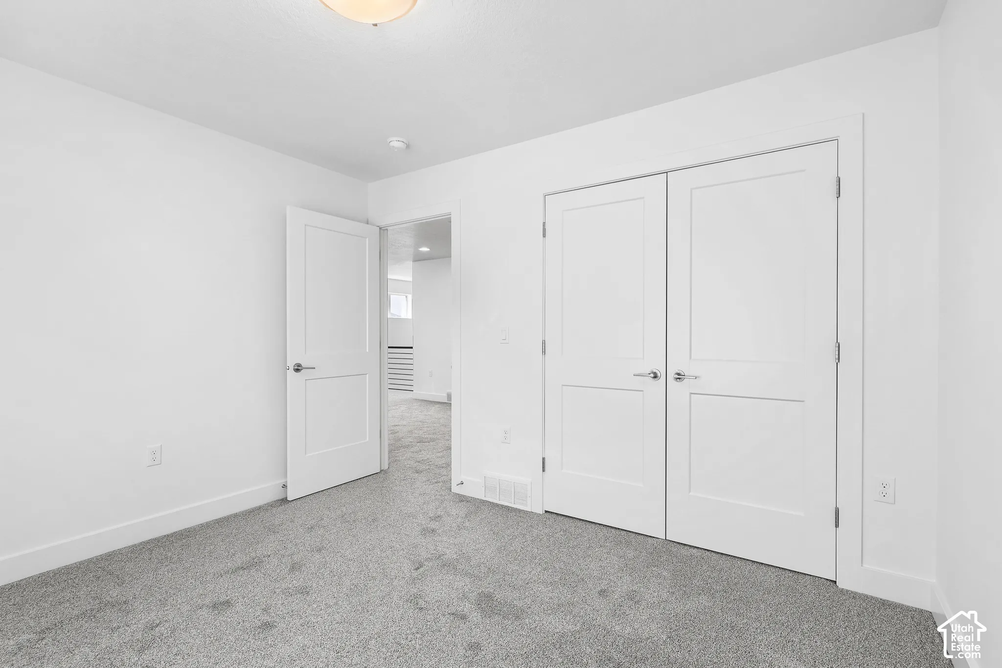Neutral gray carpeting, white painted walls, white trim, and a flush mount ceiling fixture