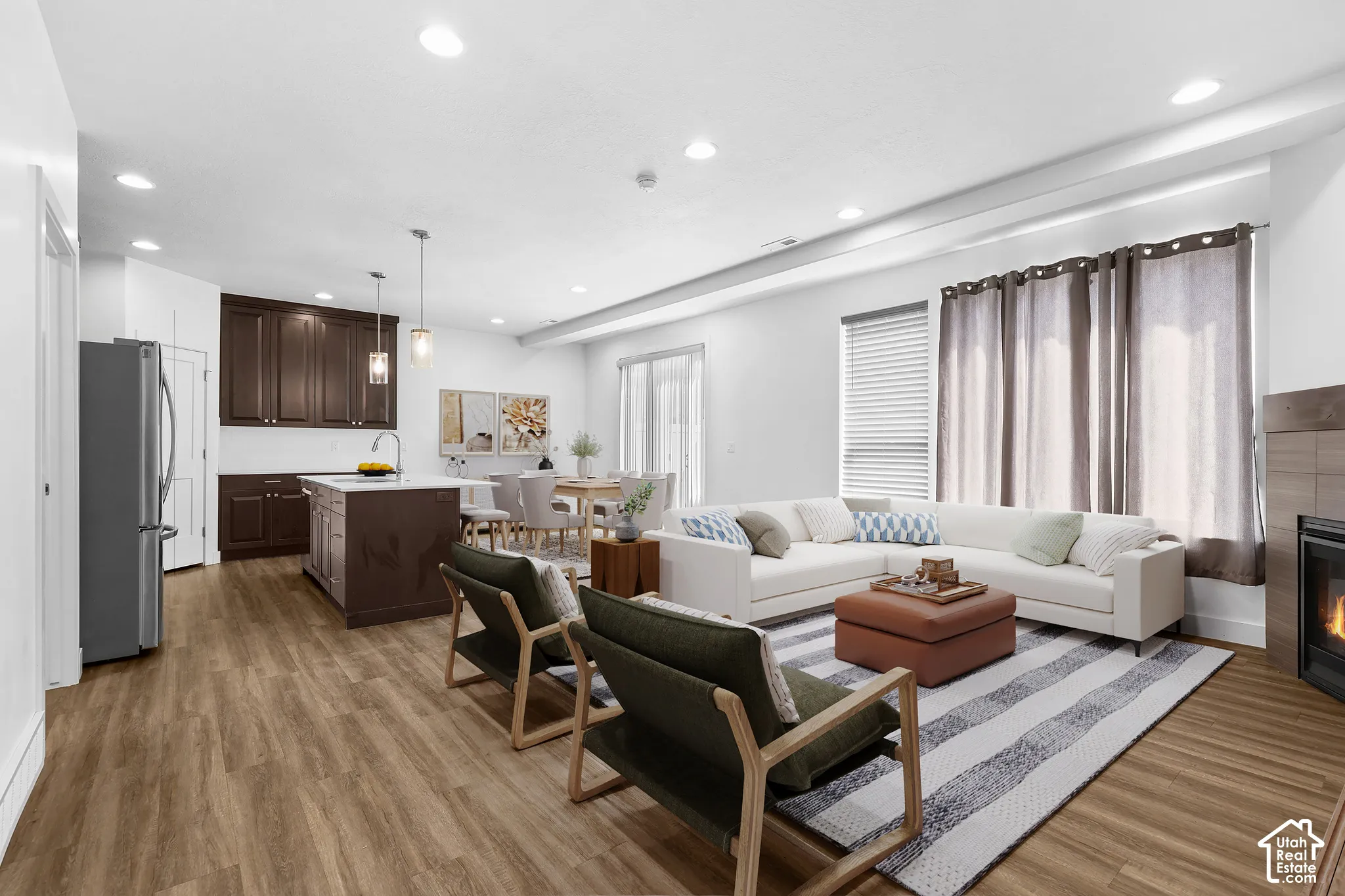 Open-concept living area featuring wood-finish flooring, recessed lighting, a built-in fireplace, and a kitchen island with pendant lighting