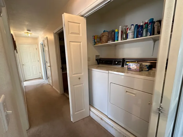 Hallway laundry closet featuring a washer and dryer, integrated shelving, bi-fold doors, and recessed lighting