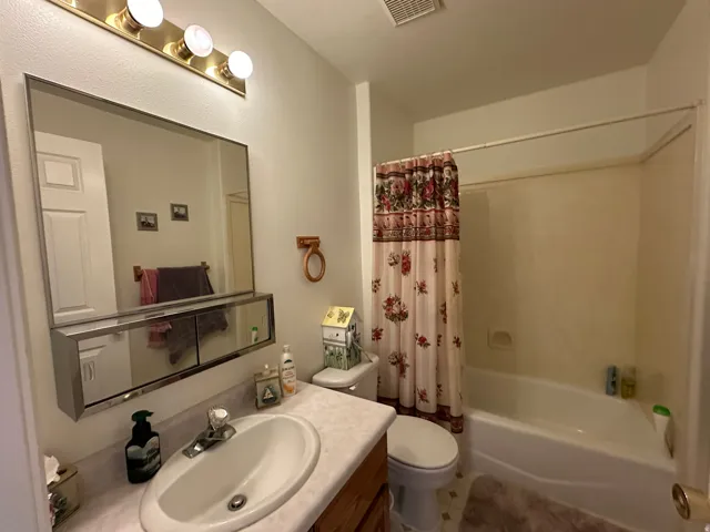 Bathroom featuring a single vanity with an oval sink, a light-colored countertop, and wood-finish cabinetry