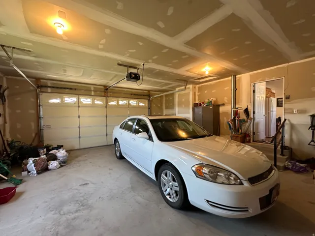 Two-car garage featuring concrete flooring, a paneled garage door with upper window inserts, and exposed ceiling joists