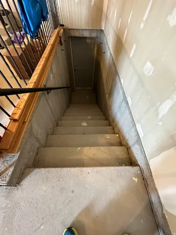 Concrete staircase featuring a dark gray paneled door at the base
