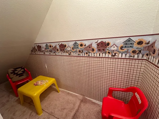 Carpeted room featuring a sloped ceiling, textured walls, and a decorative wallpaper border