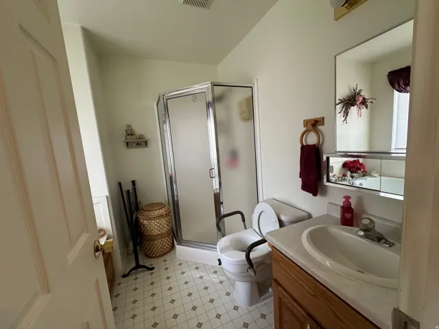 Bathroom featuring a glass-enclosed shower, single vanity with integrated sink, wood-finish cabinetry, and a mirrored medicine cabinet