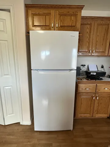 Wood-finish flooring complementing light-toned cabinetry and a white refrigerator