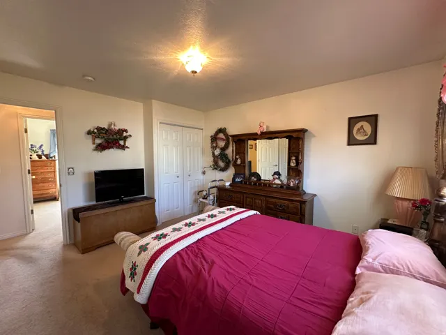 Carpeted bedroom featuring a double-door closet, a built-in ceiling light fixture, and an entryway to an adjoining room